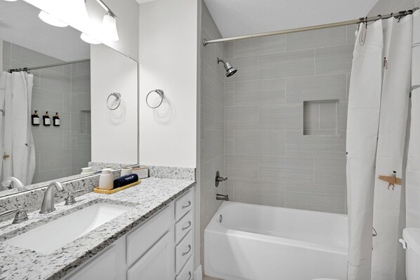A modern bathroom with a double sink, a shower with a glass enclosure, and a bathtub. - Walk2Beach, King, Parking, SelfCheckIn, Backyard, Bikes (Jacksonville Beach)