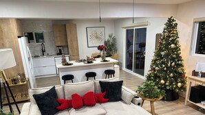 A modern living room with a sectional sofa, a Christmas tree, and a kitchen in the background.