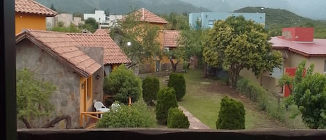 A view of a residential area with houses, a garden, and mountains in the background.