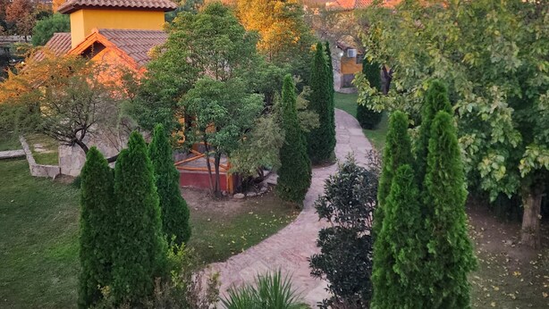 A garden with a pathway, neatly trimmed trees, and a building with a tiled roof. - Merlo Trail Lodge (Merlo)