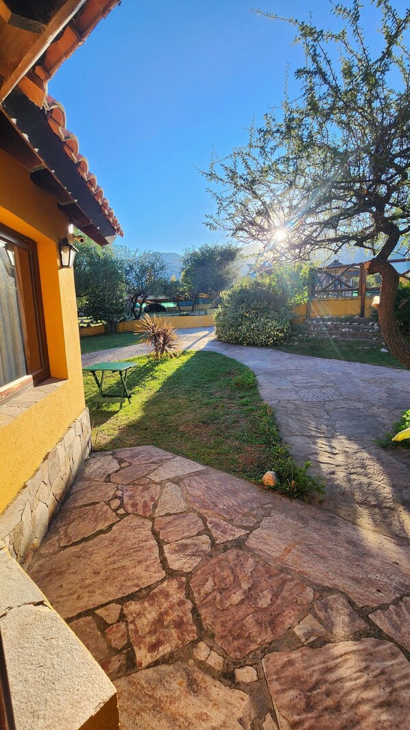 A stone pathway leading to a yellow building with a tiled roof. - Merlo Trail Lodge (Merlo)