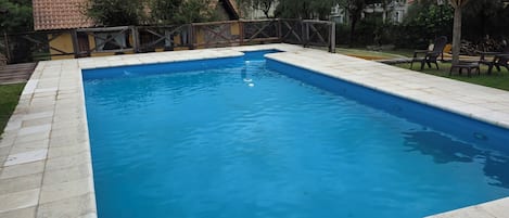 A rectangular swimming pool with a tiled edge, surrounded by a stone deck.