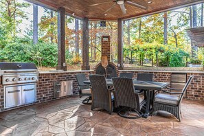 Eine Terrasse im Freien mit Grill, Grillstation und Essbereich mit Korbstühlen.