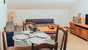 A cozy living room with a dining table set for four, a sofa, a TV stand with speakers, and a lamp. - Awesome apartment in Vrboska with WiFi (Vrboska)