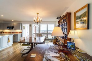 Ein Essbereich mit Holztisch, Stühlen, einer Chandelüster, einer Lampe und einem Puzzel auf dem Tisch.