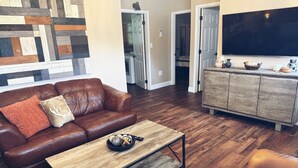 A living room with a brown leather sofa, a wooden coffee table, and a television on a cabinet.