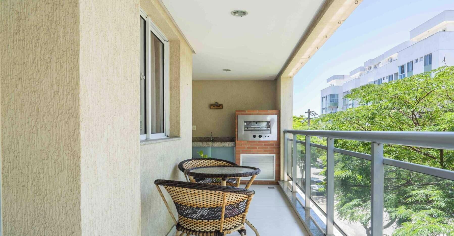 Ein Balkon mit zwei Korbstühlen und einem eingebauten Grill.
