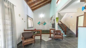 A spacious living area with a high ceiling, a staircase, and a view of the outdoors.