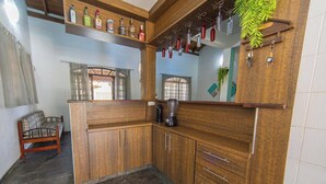 A kitchen with wooden cabinets, a coffee machine, and a shelf with liquor bottles.