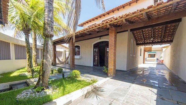 A courtyard with a tiled floor, palm trees, and a covered patio area.