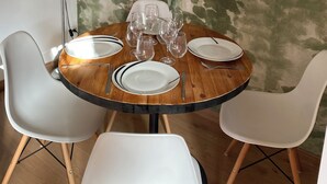 Una mesa de comedor redonda con sillas blancas, dispuesta con platos, vasos y cubiertos.