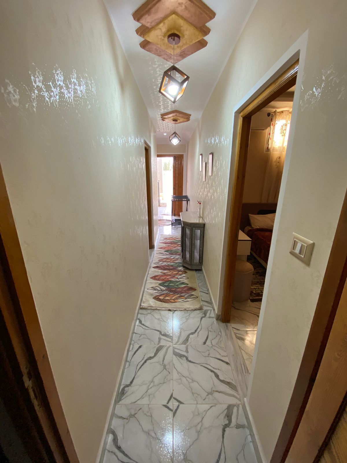 Un couloir doté d’un sol en marbre, de poutres en bois au plafond et d’un tapis à motifs.