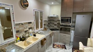 Una cocina moderna con encimeras de granito, microondas integrado y refrigerador de acero inoxidable.