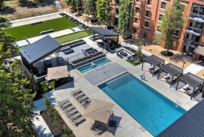 Ein Poolbereich auf dem Dach mit mehreren Pools, Liegestühlen und Sonnenschirmen.