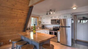 Een moderne keuken met houten wanden, roestvrijstalen apparatuur en een centraal kookeiland met krukken.