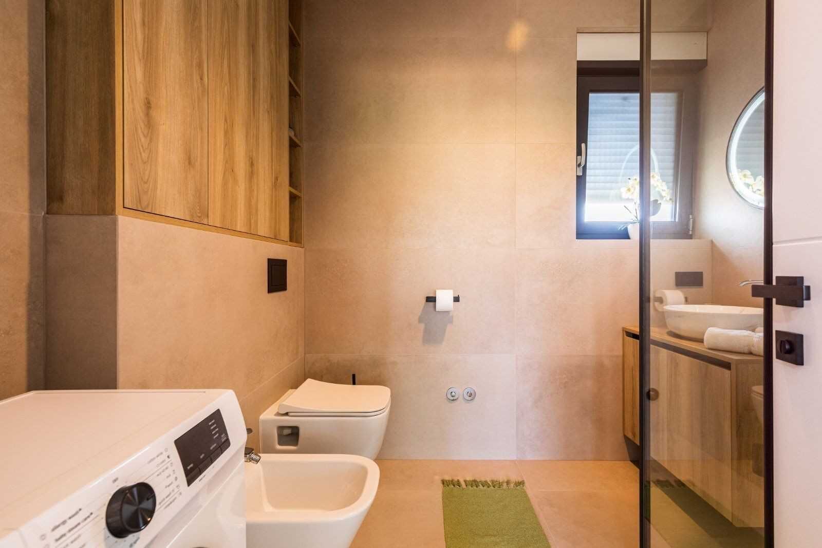 Een moderne badkamer met toilet, bidet en een klein wastafeltje.