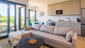 A modern kitchen with a built-in microwave, oven, and sink. There is a large window providing a view of the outdoors. - Luxury apartment LaRiv II with pool (Krk)