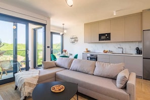 A modern kitchen with a built-in microwave, oven, and sink. There is a large window providing a view of the outdoors. - Luxury apartment LaRiv II with pool (Krk)
