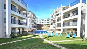 Un moderno hotel a più piani con balconi, piscina e prato curato.