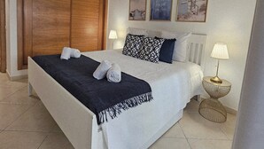 Una camera da letto ordinata con un letto grande, un'armadio in legno e due abat-jour.