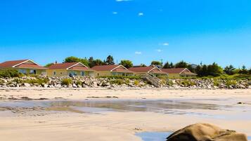 A beachfront property with multiple houses, a sandy beach, and a rocky shoreline.