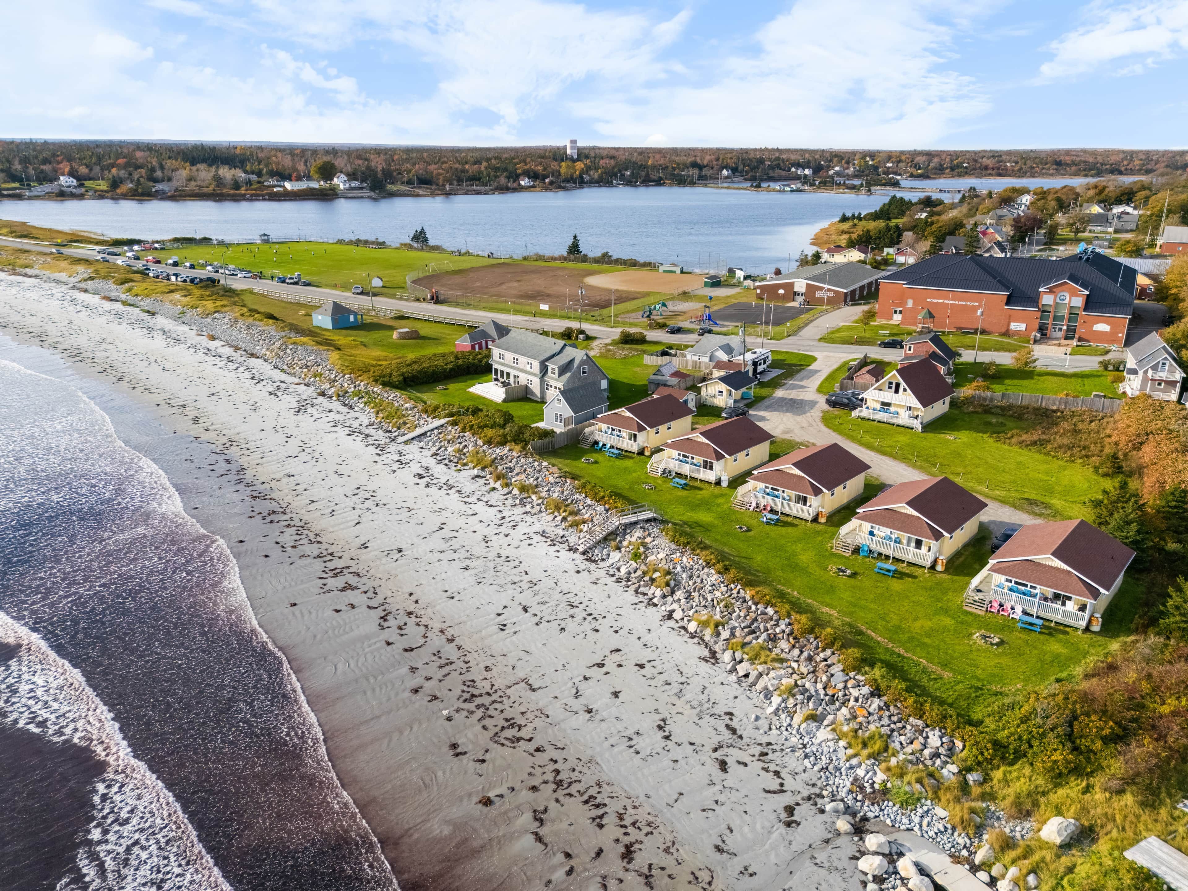 Een woongebied aan de kust met huizen, een strand en een meer.
