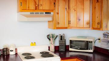 Una cocina con armarios de madera, una estufa blanca, un microondas y diversos utensilios de cocina.
