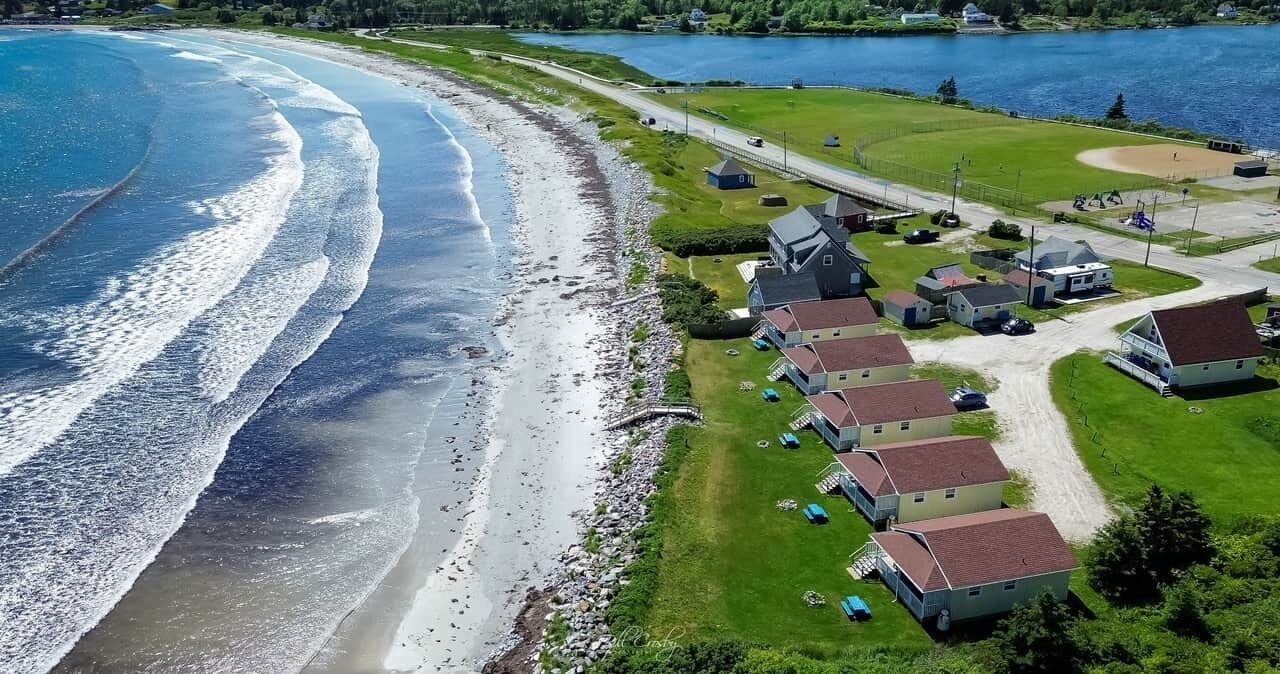 A coastal property with a beach, houses, and a road.