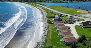 A coastal property with a beach, houses, and a road.