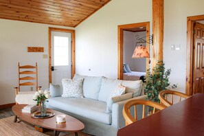 Una sala acogedora con un sofá azul claro, sillas de madera, una mesa de centro y techo de madera.