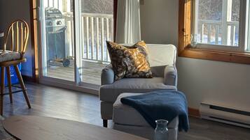 A cozy living room with a grey armchair, a wooden chair, and a small table.