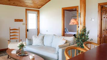 En hyggelig stue med en lyseblå sofa, træstole, et sofabord og et træloft.