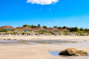 A beachfront property with multiple houses, a sandy beach, and a rocky shoreline.