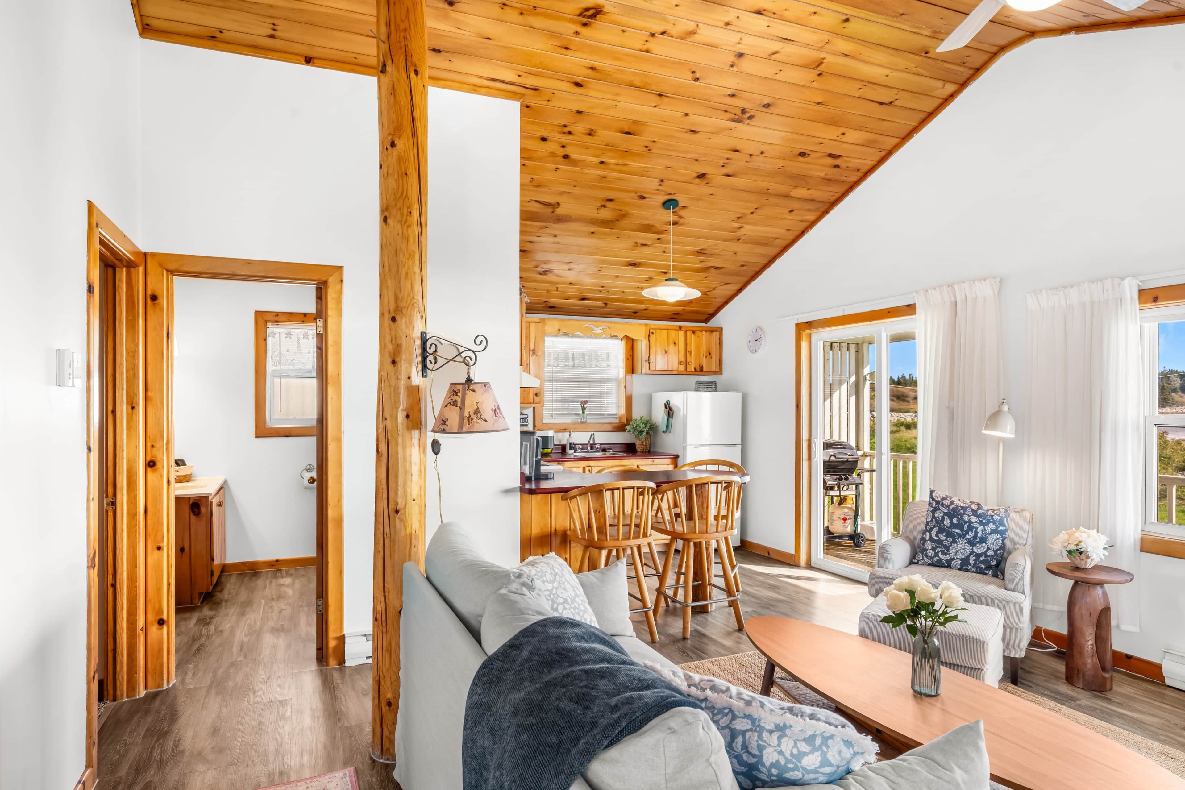 A cozy interior with a wooden ceiling, a dining area, and a view through a glass door.