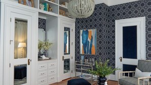 A room with a white wardrobe, a blue sofa, and a chandelier. - Pandora's Manor Bed & Breakfast (High Point)