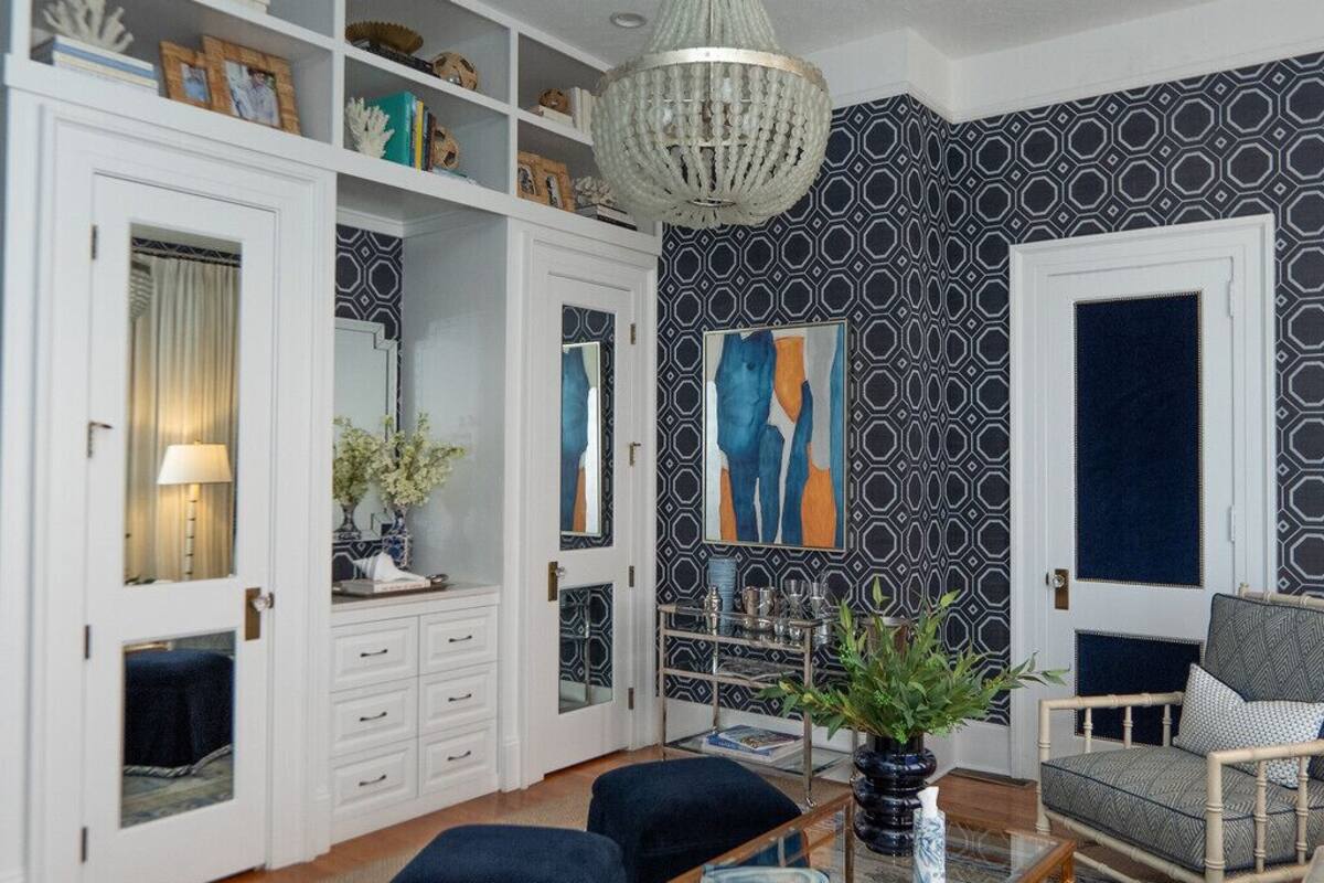 Ein Zimmer mit einem weißen Kleiderschrank, einem blauen Sofa und einer Chandelüster.