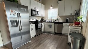 A modern kitchen with white cabinets, stainless steel appliances, and a wooden floor. - Peaceful Lakeside Retreat - Cozy 3BR Waterfront Home - Secure Parking (Clearlake)