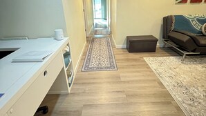 A hallway with a desk, a rug, a couch, and a painting on the wall. - Peaceful Lakeside Retreat - Cozy 3BR Waterfront Home - Secure Parking (Clearlake)