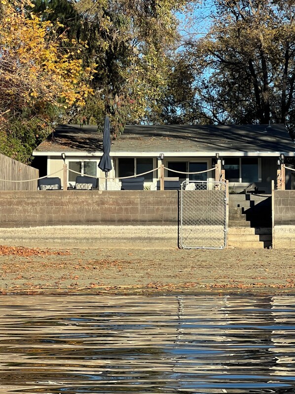 A building with a covered patio area, a fenced swimming pool, and a staircase leading to a deck. - Peaceful Lakeside Retreat - Cozy 3BR Waterfront Home - Secure Parking (Clearlake)