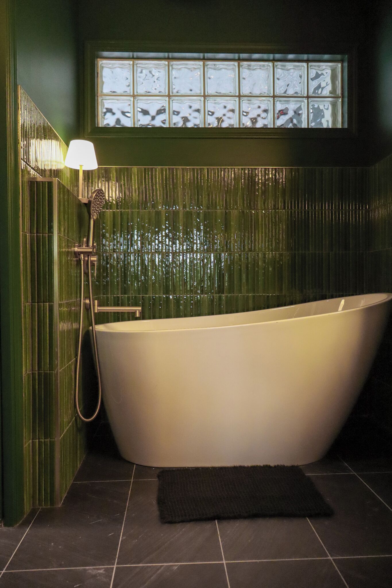 A bathroom with a freestanding bathtub, a window above the tub, and a towel rack.