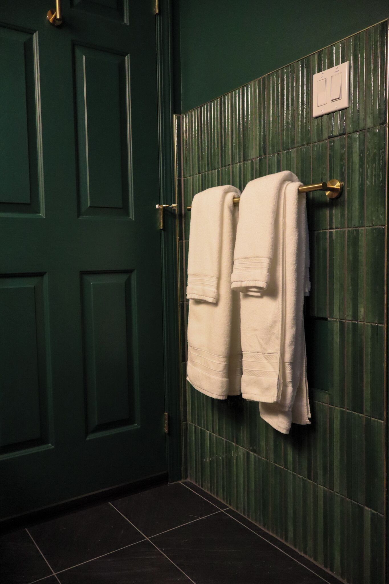 A green door with a towel rack holding two towels.