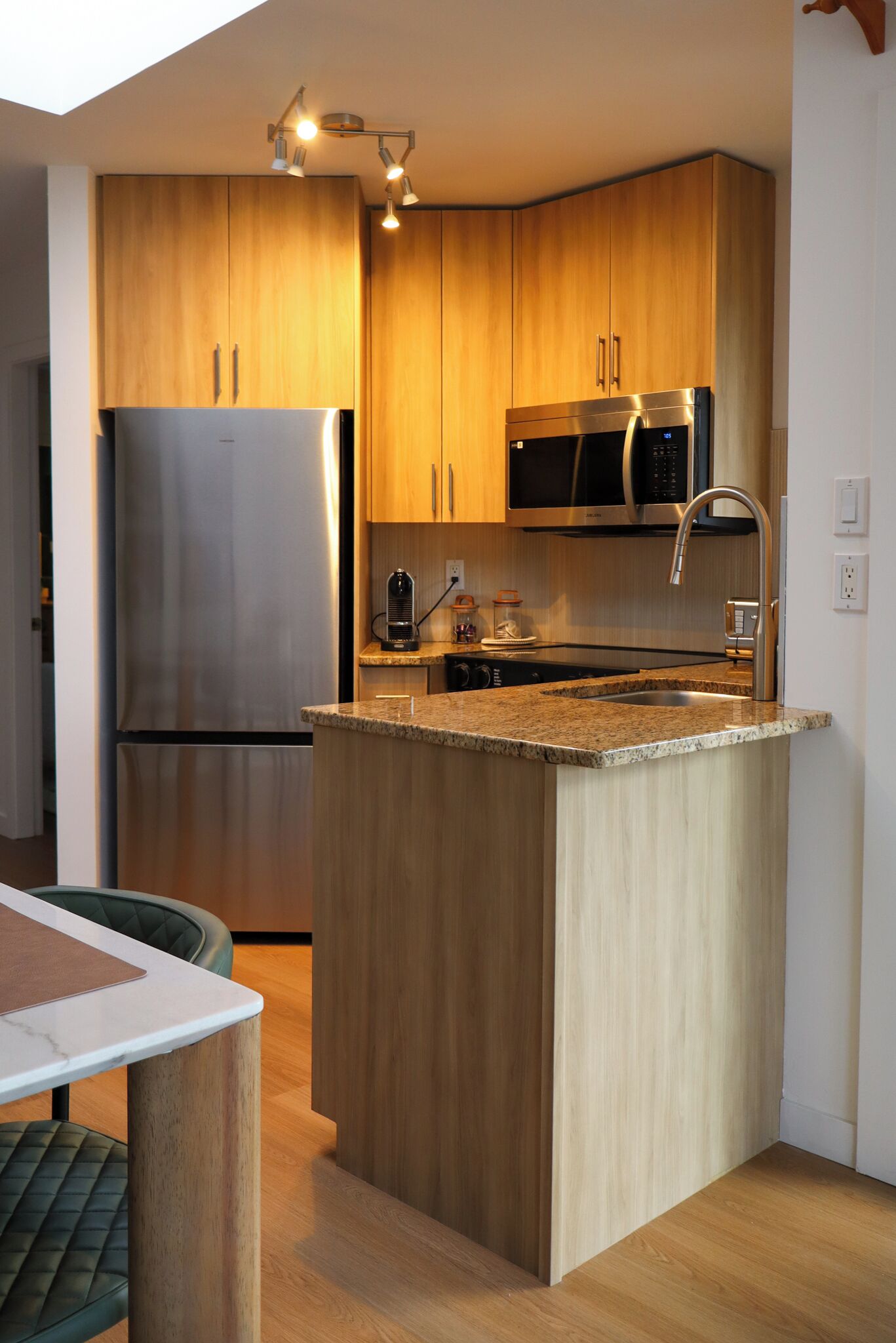 A modern kitchen with wooden cabinets, stainless steel appliances, and a granite countertop island.
