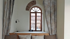 A cozy room with a wooden bench, a window with a view, and curtains.