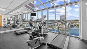 A gym with various exercise machines, large windows offering a view of a cityscape. - Prince Resort at Cherry Grove Pier with lazy river (North Myrtle Beach)