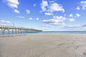 A beach with a pier extending into the ocean. - Prince Resort at Cherry Grove Pier with lazy river (North Myrtle Beach)