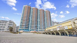 A high-rise hotel with multiple balconies, a beachside location, and a sandy foreground. - Prince Resort at Cherry Grove Pier with lazy river (North Myrtle Beach)