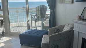 A living room with a view of the ocean, a white fireplace, and a blue ottoman. - Prince Resort at Cherry Grove Pier with lazy river (North Myrtle Beach)