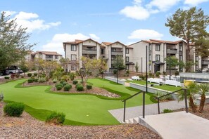 A residential building with multiple balconies, a landscaped garden with a putting green, and a paved walkway. - Bright 2BR Near ASU, Pool, Grill, Prking (Tempe)