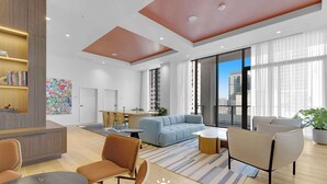 Un hall d’hôtel moderne doté d’un espace salon, d’un comptoir d’accueil et de grandes fenêtres offrant une vue sur la ville.