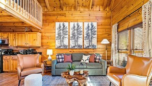Ein gemütliches Blockhaus-Interieur mit Holzausstattung, einer Sofaecke, einem Couchtisch und einem Essbereich.